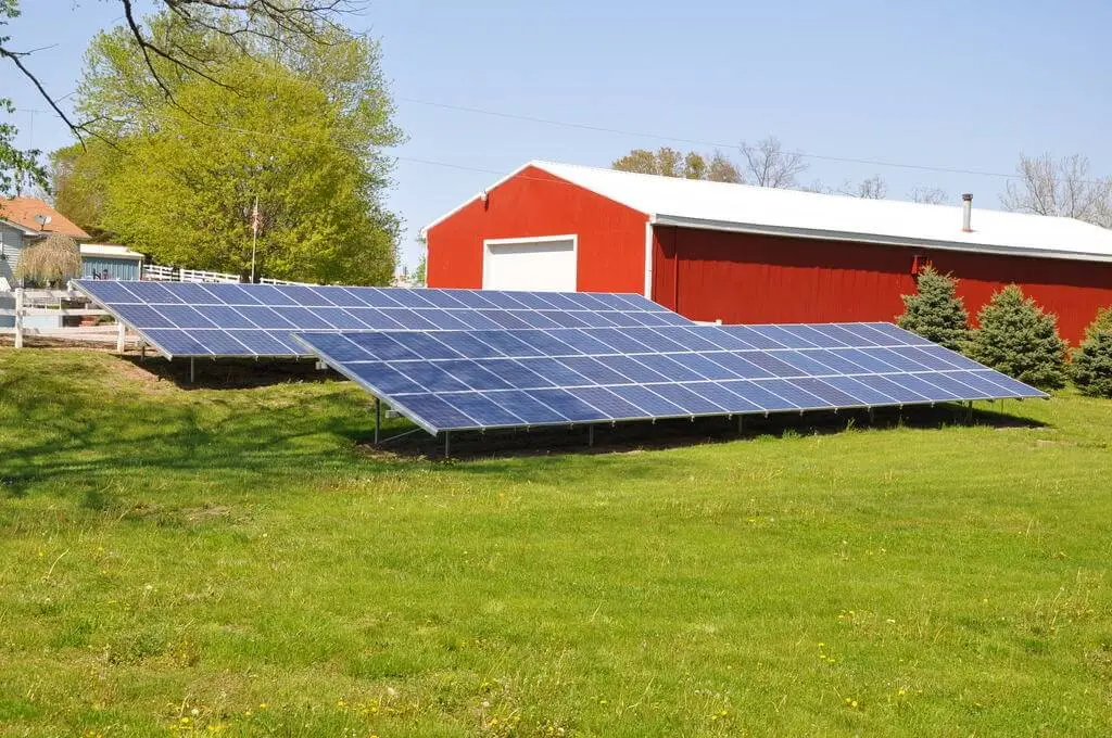 Solar panels in front of red barn.