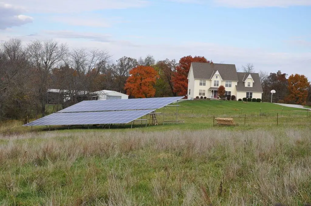 Solar panels in field near house.